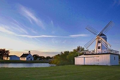 This is a picture of a farm with a windmill on the land.